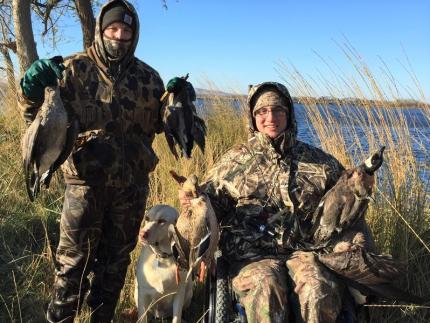 Disabled hunter poses with harvested ducks and companion.
