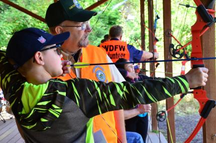 Boy prepares to shoot an arrow at a National Hunting and Fishing Day event