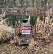 A closed area sign on a small dilapidated boardwalk.