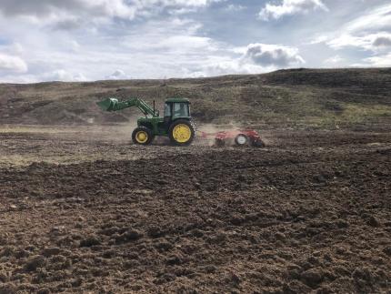 A tractor pulling a set of discs to prepare the land for platning.