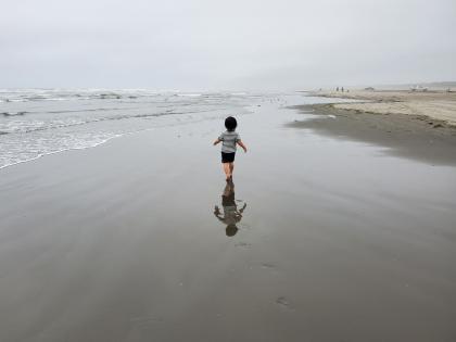 Child walks on beach on a cloudy day