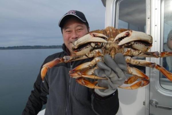 Man holds up crab while on boat