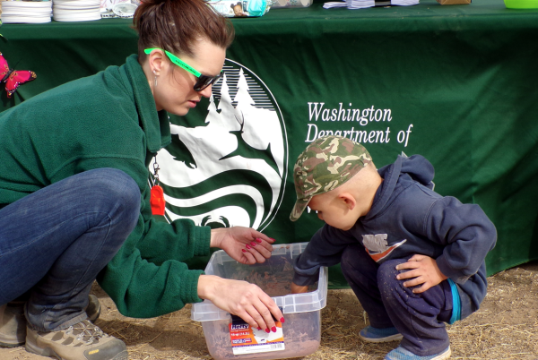 WDFW staff at an event booth with kid. 