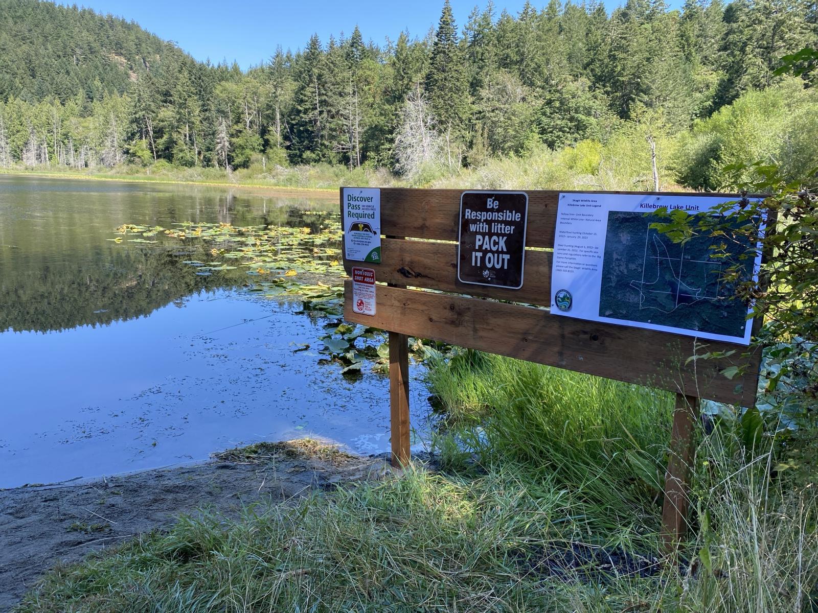 Signage at a lake surrounded by woods