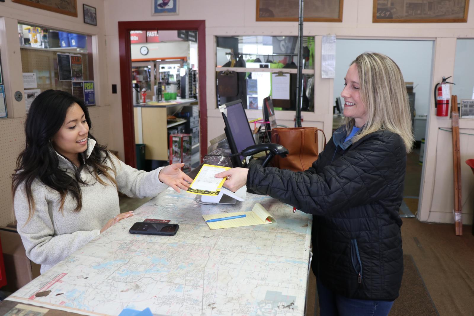 A woman buys a hunting license from a license dealer.
