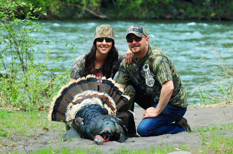 Two successful spring turkey hunters near a river.