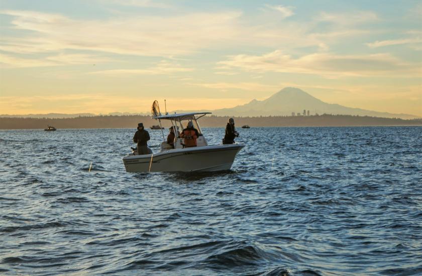 Four anglers fishing from a boat on Puget Sound with Mt. Rainier in the distance