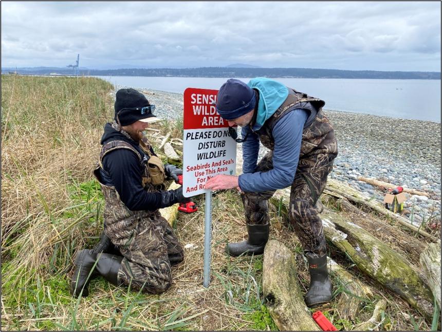 Technicians installing signage on Rat Island.