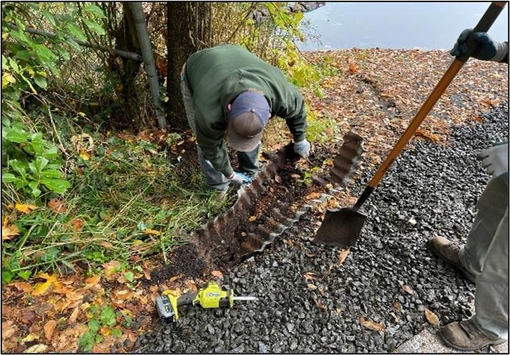 Two staff members working to spread gravel at Offutt Lake. 