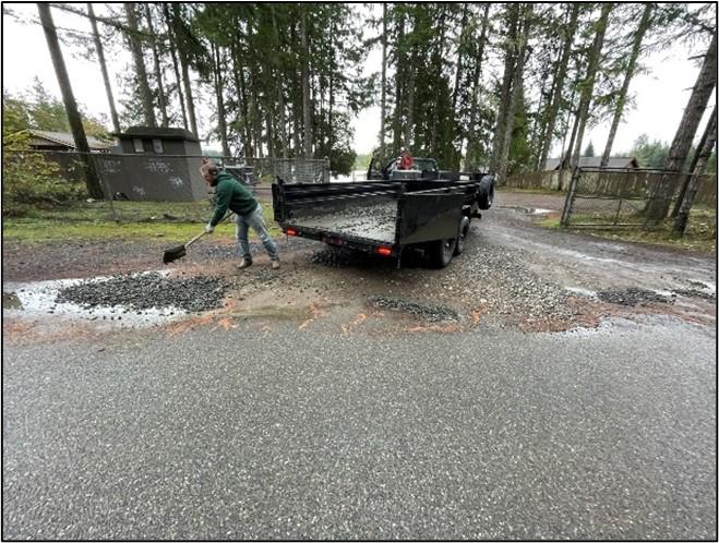 A person spreading gravel with a shovel at Island Lake. 