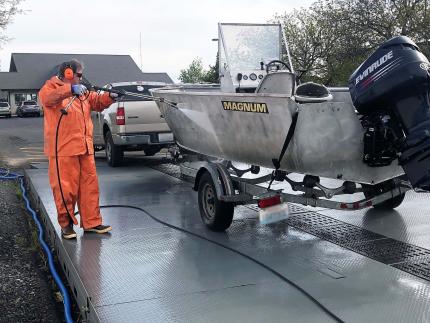 Working with protective gear sprays boat with hot water