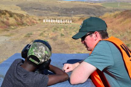 Hunter education instructor teaches young boy safe firearms practices
