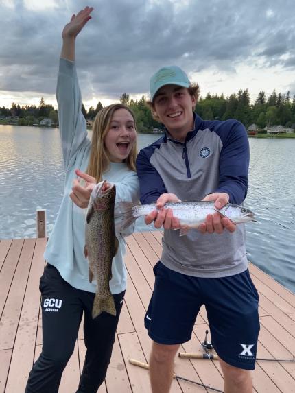 Two young people show fish they caught