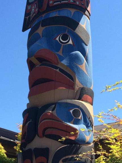Cedar carved welcome pole painted in blue, red, and black