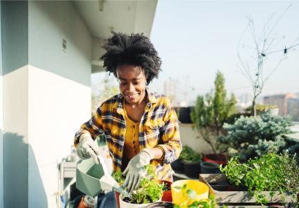 Woman works in a container garden on a balcony