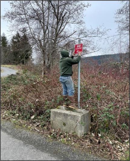 A person fixing a sign by the road