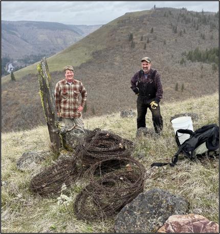 Volunteers Haskell and Ihrig with reels of old barb wire.