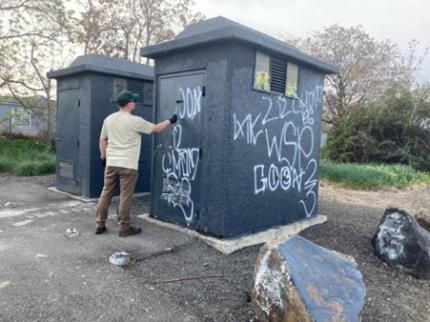 A person removing graffiti off a structure.