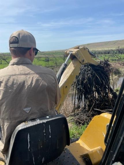 Manderbach clearing a waterway with a tractor.