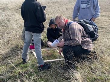 A handful of people identifying grasses and forbs.