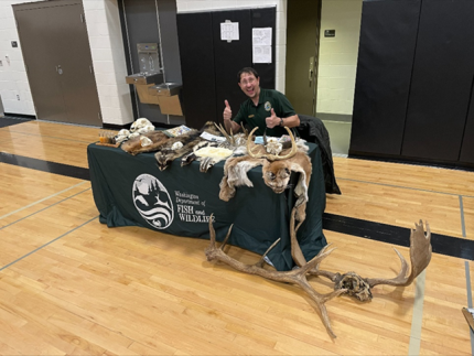 Maikis with a WDFW table set up in a gym.