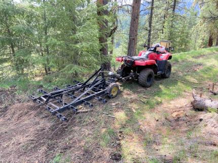 An all-terrain vehicle with seeder and harrow.