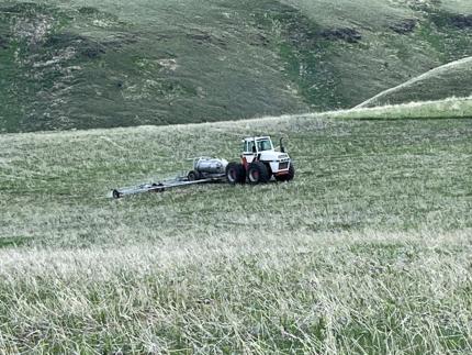 A tractor pulling a 50-foot sprayer through a field.