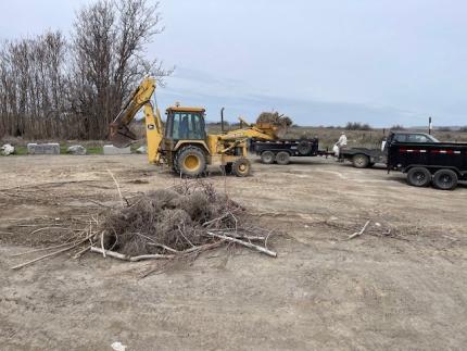A pile of branches and debris with a tractor nearby.
