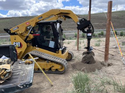 A tractor drilling a new post hole.