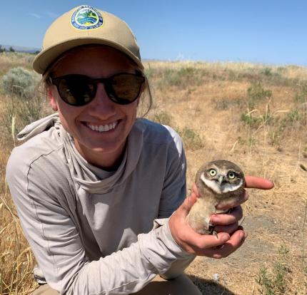 Biologist Wampole with juvenile burrowing owl banded and ready for release.