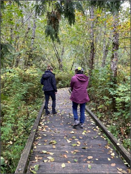 Two people walking down a boardwalk at the Theler Welands. 