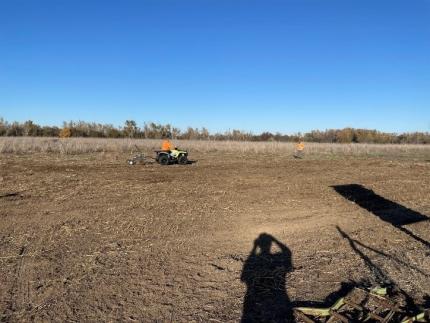 Heimgartner raking the vegetation debris off the Stovall Field in preparation for planting. 