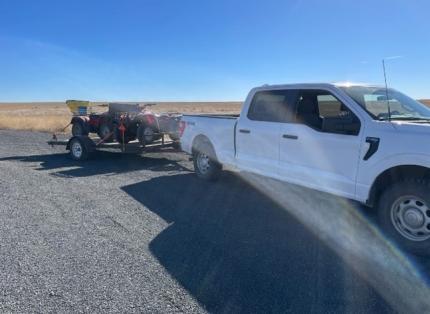 A truck pulling equipment on a trailer.