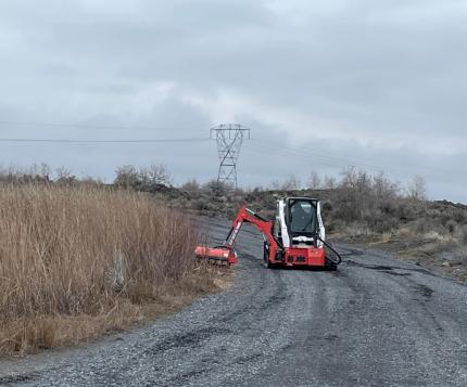 A tractor mower mowing the sides of a road