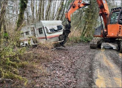 An abandoned RV being pulled out from the woods