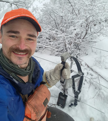 A man with a mule deer GPS collar