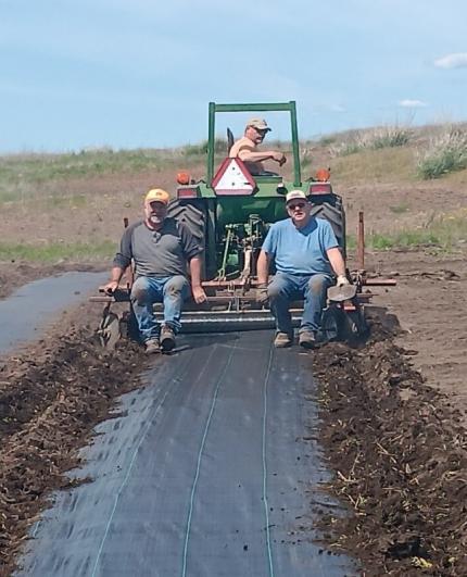 Three people on a tractor during the ALEA shrub planting project. 