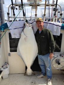 Angler poses by 140-pound halibut he caught from Puget Sound 