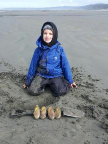 Kid smiling with just dug razor clams.
