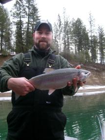 A man holds up a trout he caught in winter at Lake Roosevelt