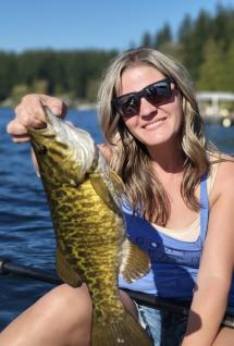Woman holds up bass fish
