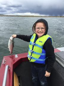 A little boy holds a trout
