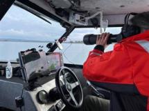 Biologist with binoculars in watercraft