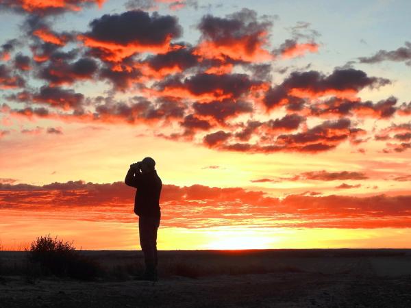 Hunter looks through binoculars at sunrise.