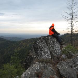 A hunter sits on a rock outcropping